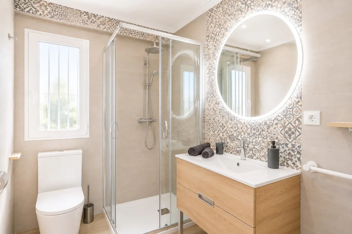 Baño con ducha, espejo redondo iluminado y mueble de madera