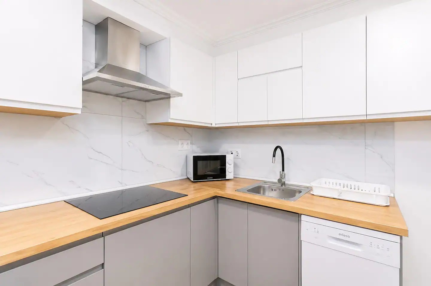 Cocina en L con encimera de madera y muebles blancos