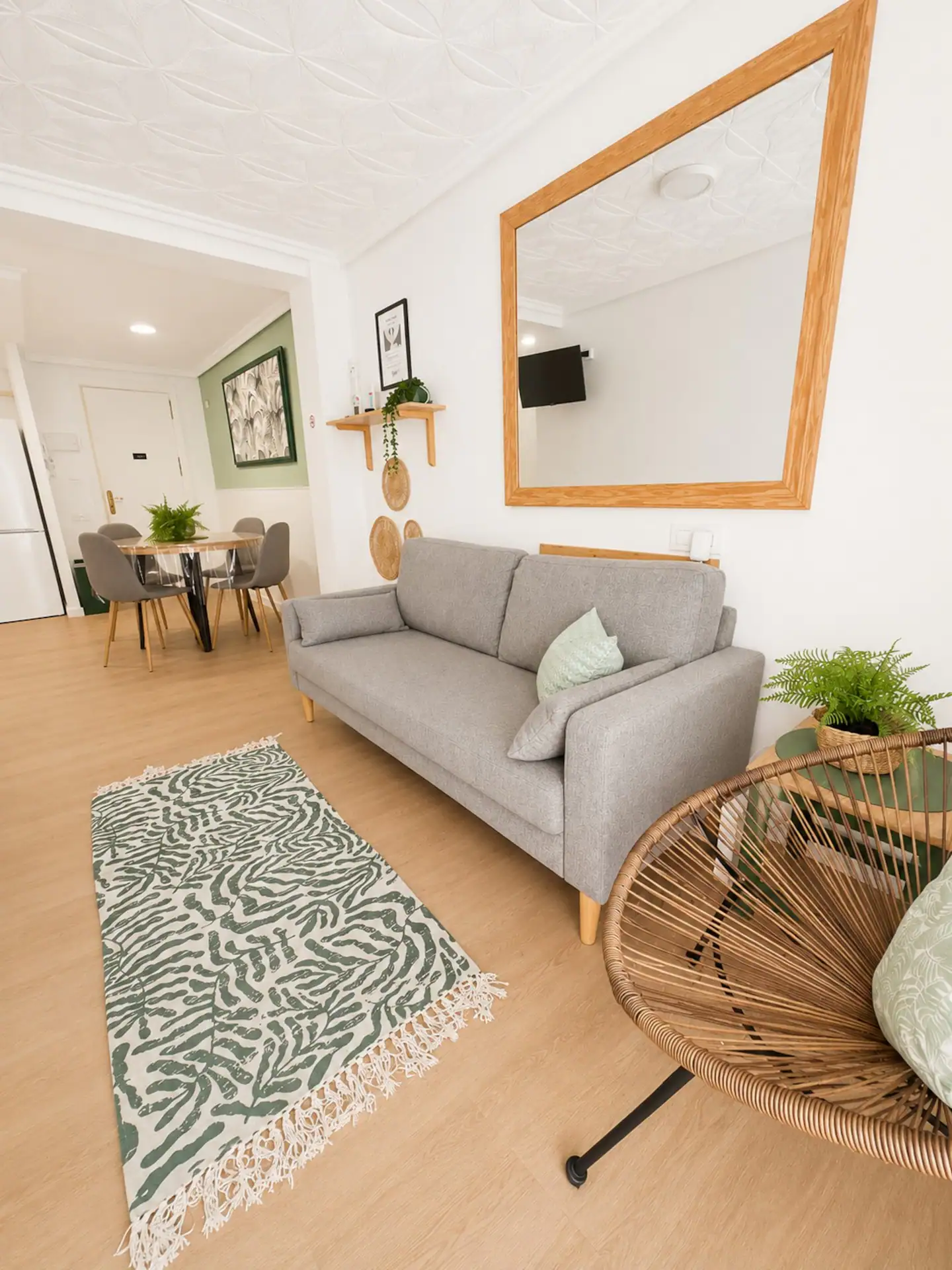 Salón del apartamento del Cabanyal, con sofá gris y paredes en verde salvia