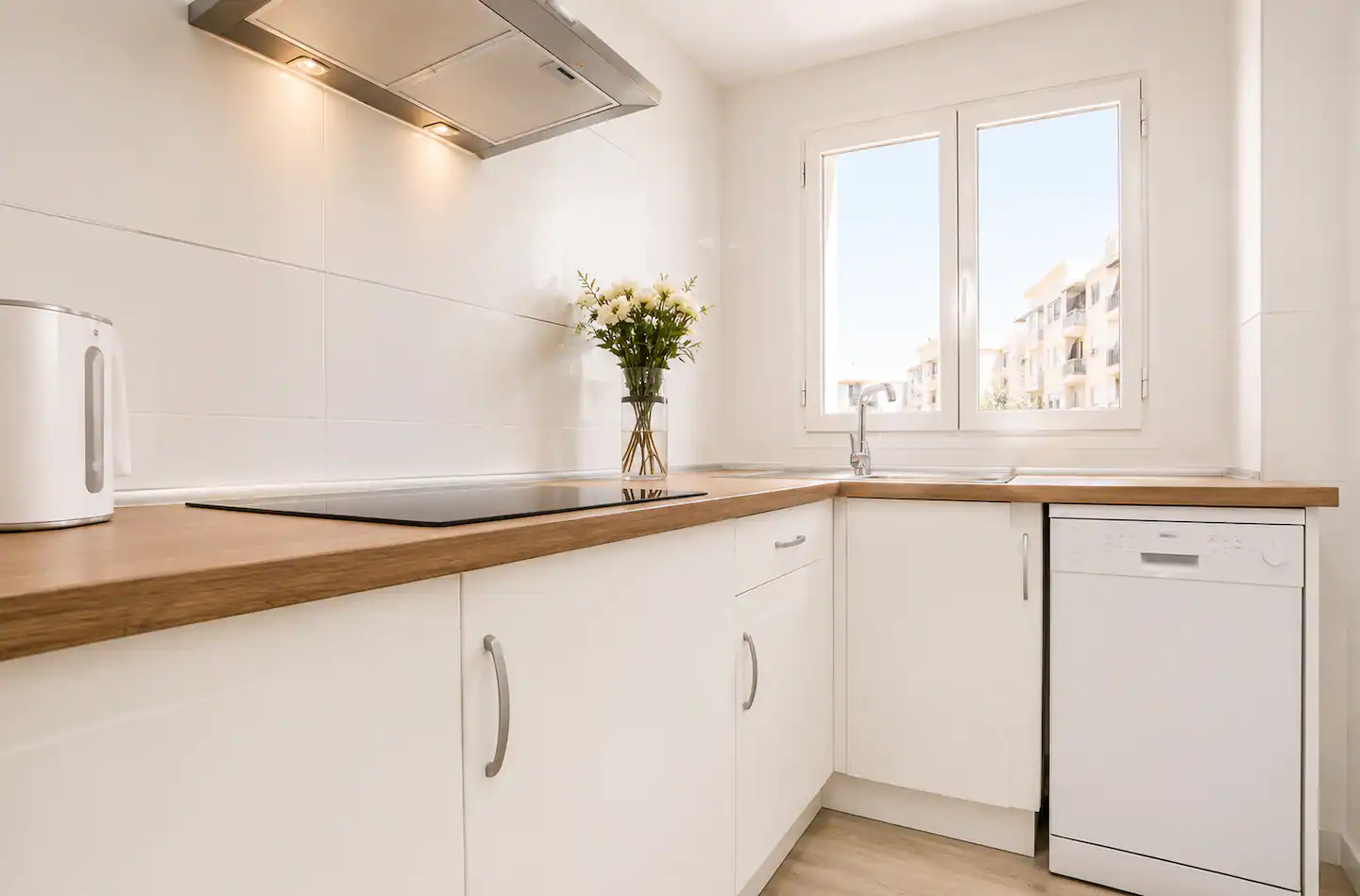 Cocina blanca con encimera de madera y campana extractora